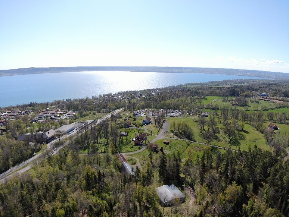 Vy över landskap med hus, skog, väg och vatten.