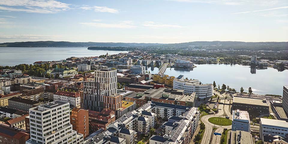 Vy över stad i solnedgång. Bro, byggnader och mycket vatten.