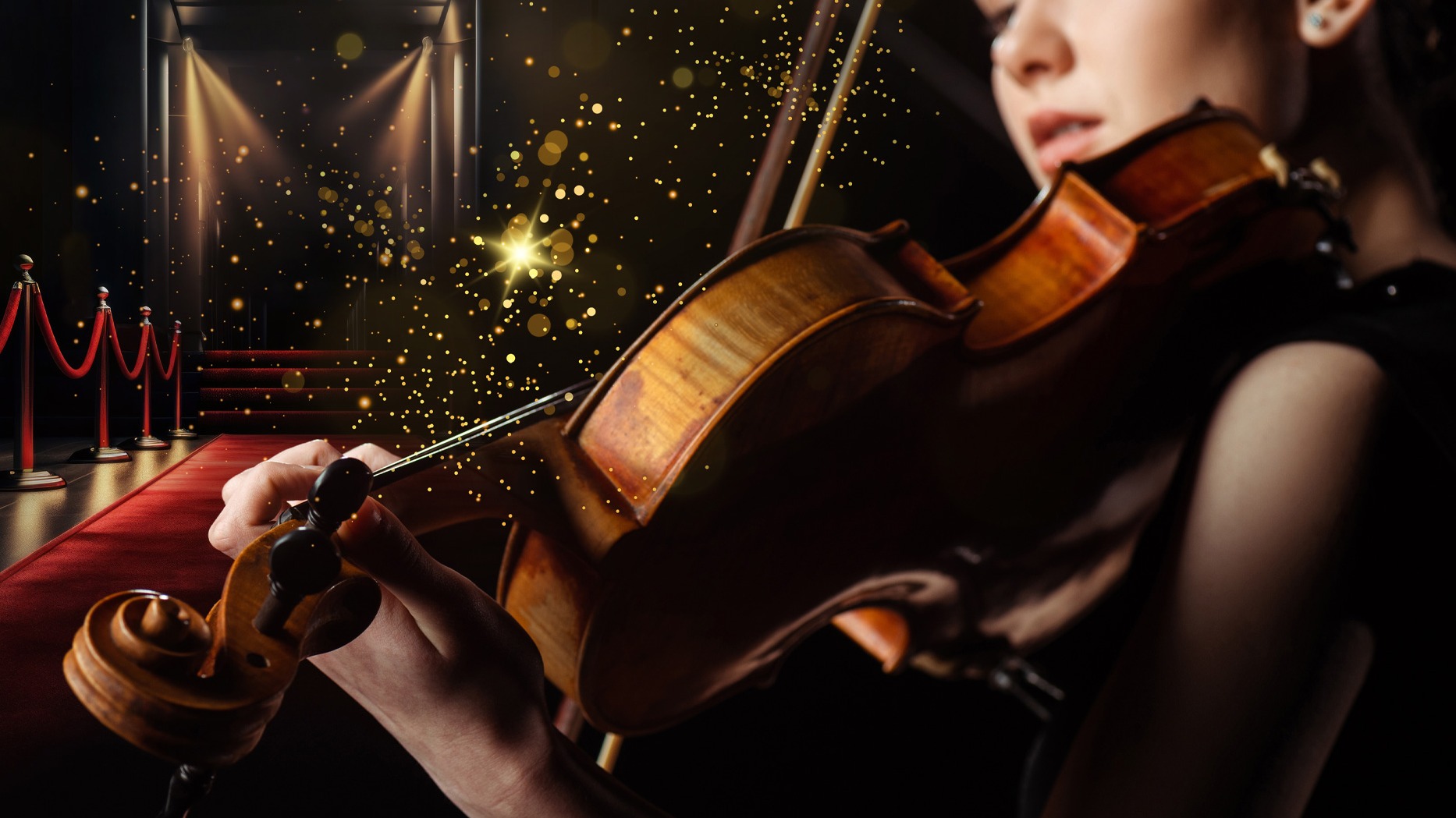 En violinist spelar på sitt instrument framför en röd matta och strålkastare.