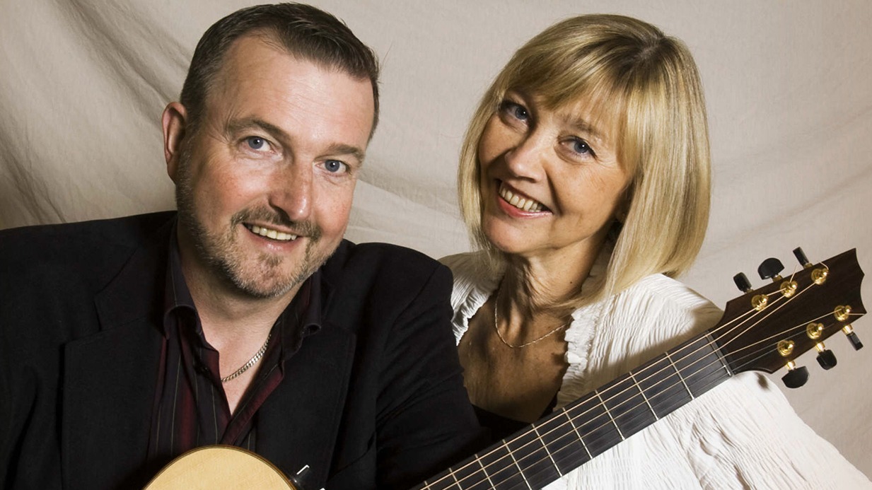 Ehrling Eliasson och Titti Sjöblom poserar framför kameran med en gitarr.