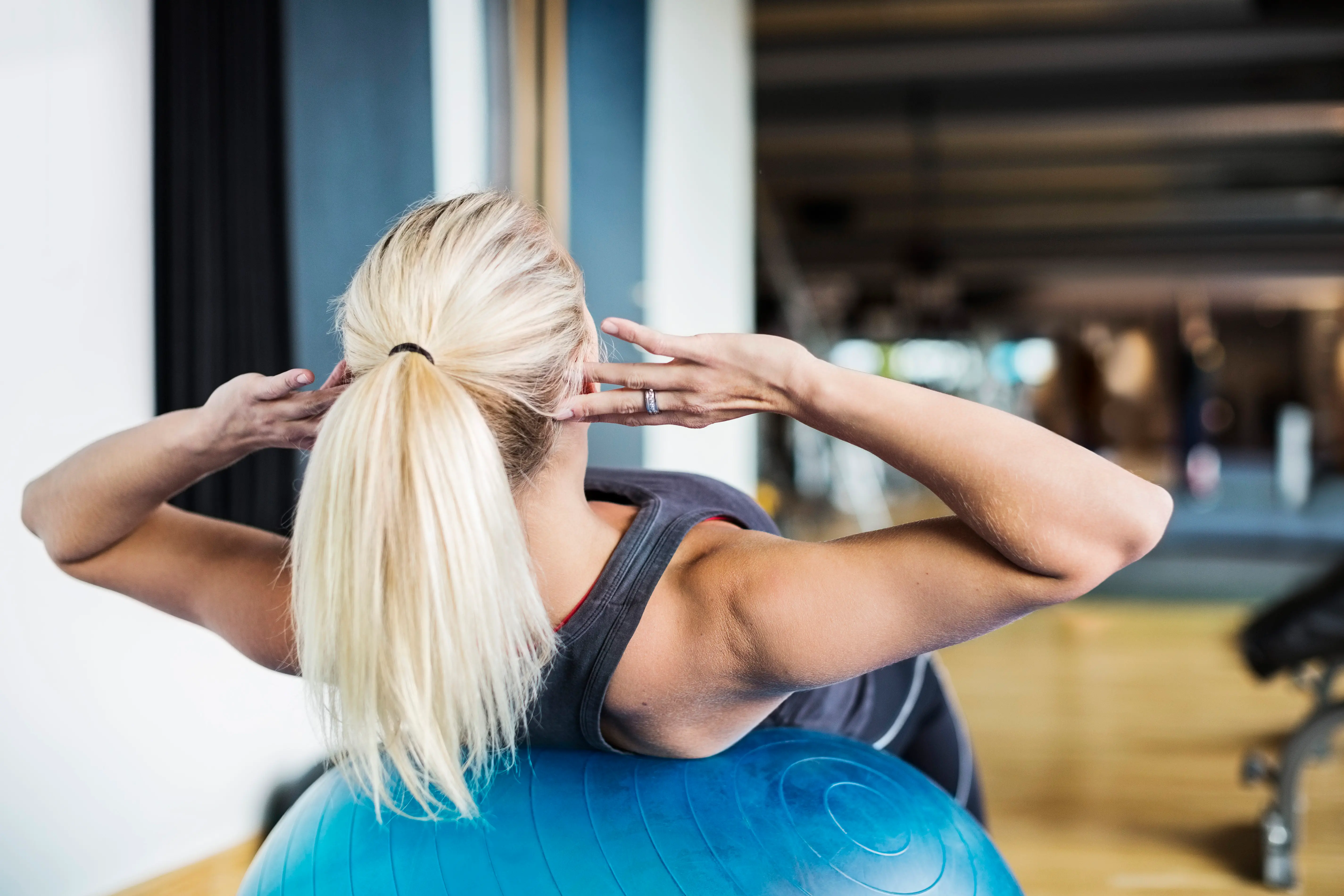 Blond person tränar på en pilatesboll. 