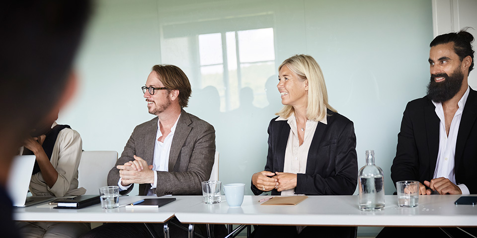 Tre glada personer i ett konferensrum.