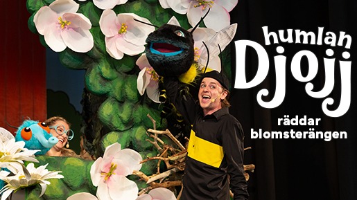 Två personer håller i varsin docka föreställandes en humla och ett blått kryp. Bildtext: humlan Djojj räddar blomsterängen.