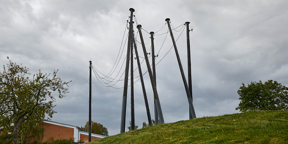 Sju höga telefonstolpar i trä och metall står i en cirkel.