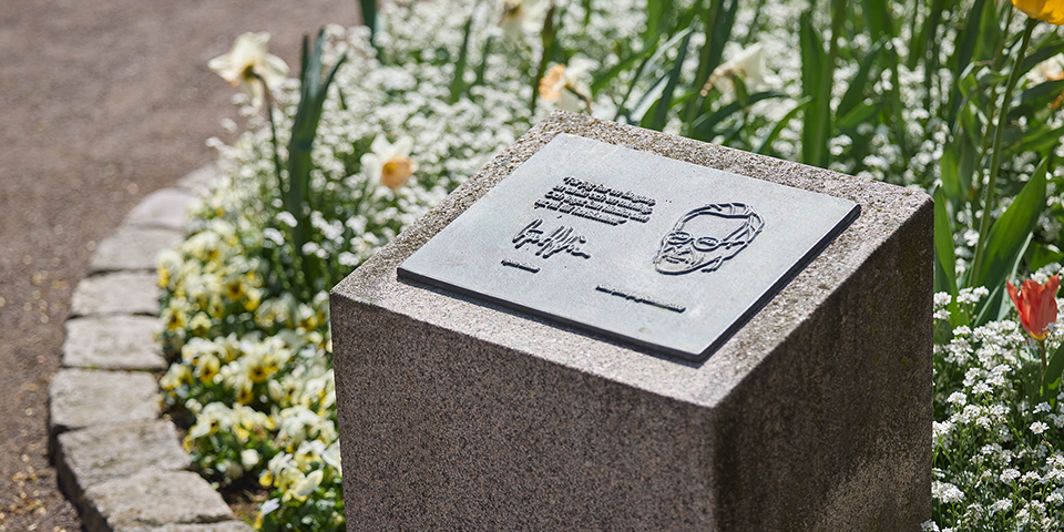 Bronsrelief placerad mitt i en blomsterrabbatt.