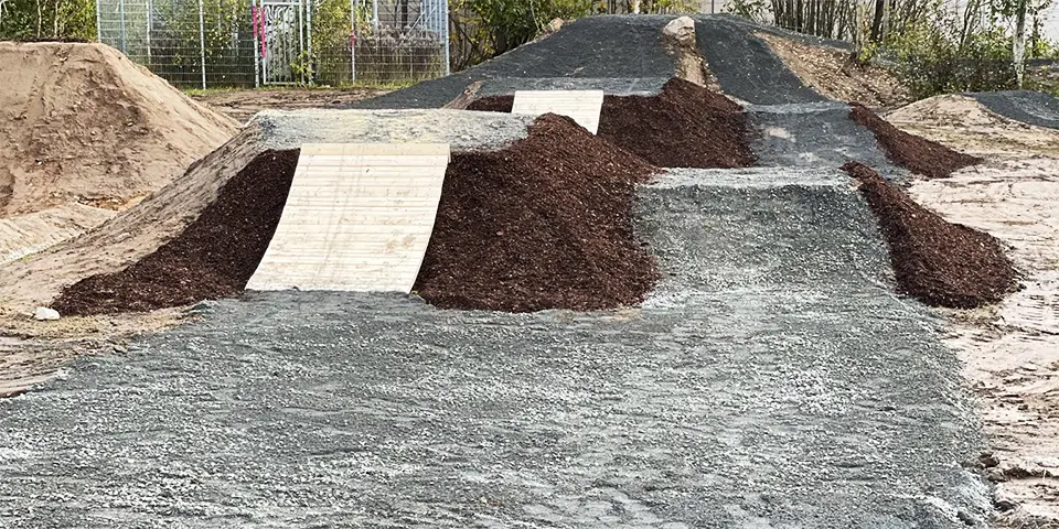 En pumptrack på grå grusplan.