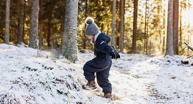 Barn som promenerar i vinterskog.