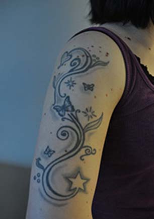 En arm med en tatuering som består av fjärilar och stjärnor.