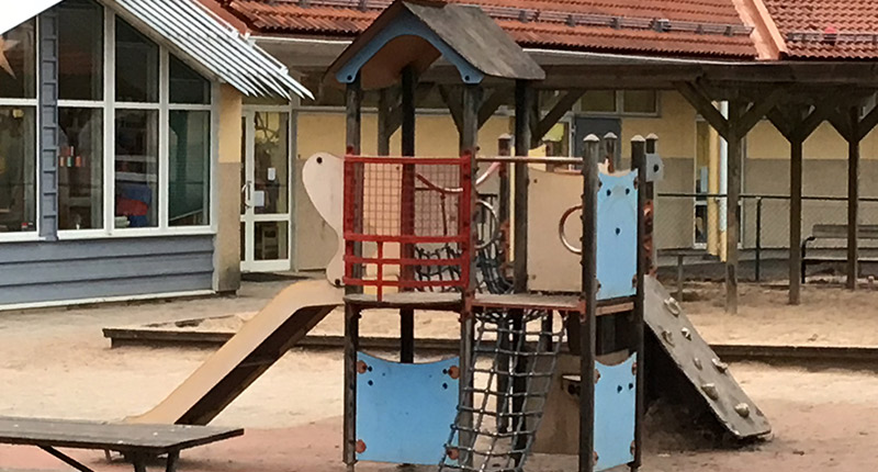 Rutschkana med två våningsplan. I bakgrunden husvägg med fönster.