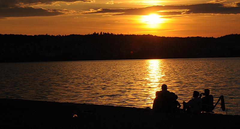 Människor på stranden i solnedgången.