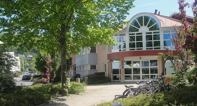 Trädgårdens äldreboende utifrån. Inglasad entré. Grönska.