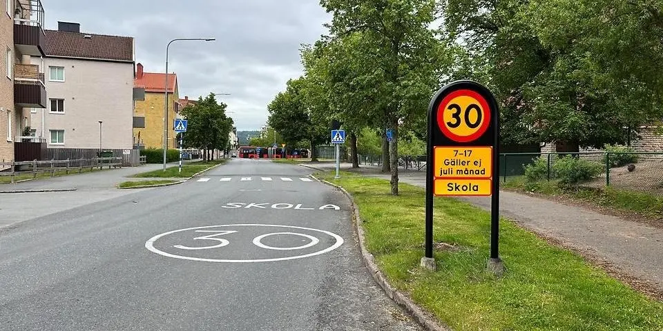 En gata med hastighetsskylt "30" och texten "Skola" och "30" målat i gatan.