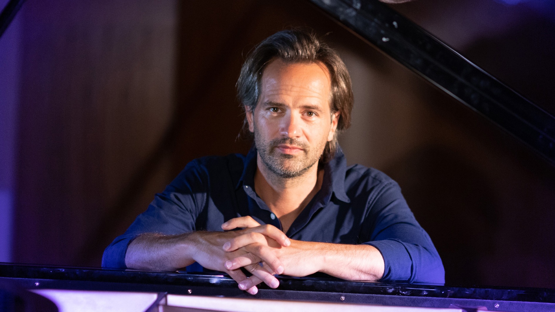 Pianisten Peter Jablonski sitter vid flygeln och tittar in i kameran