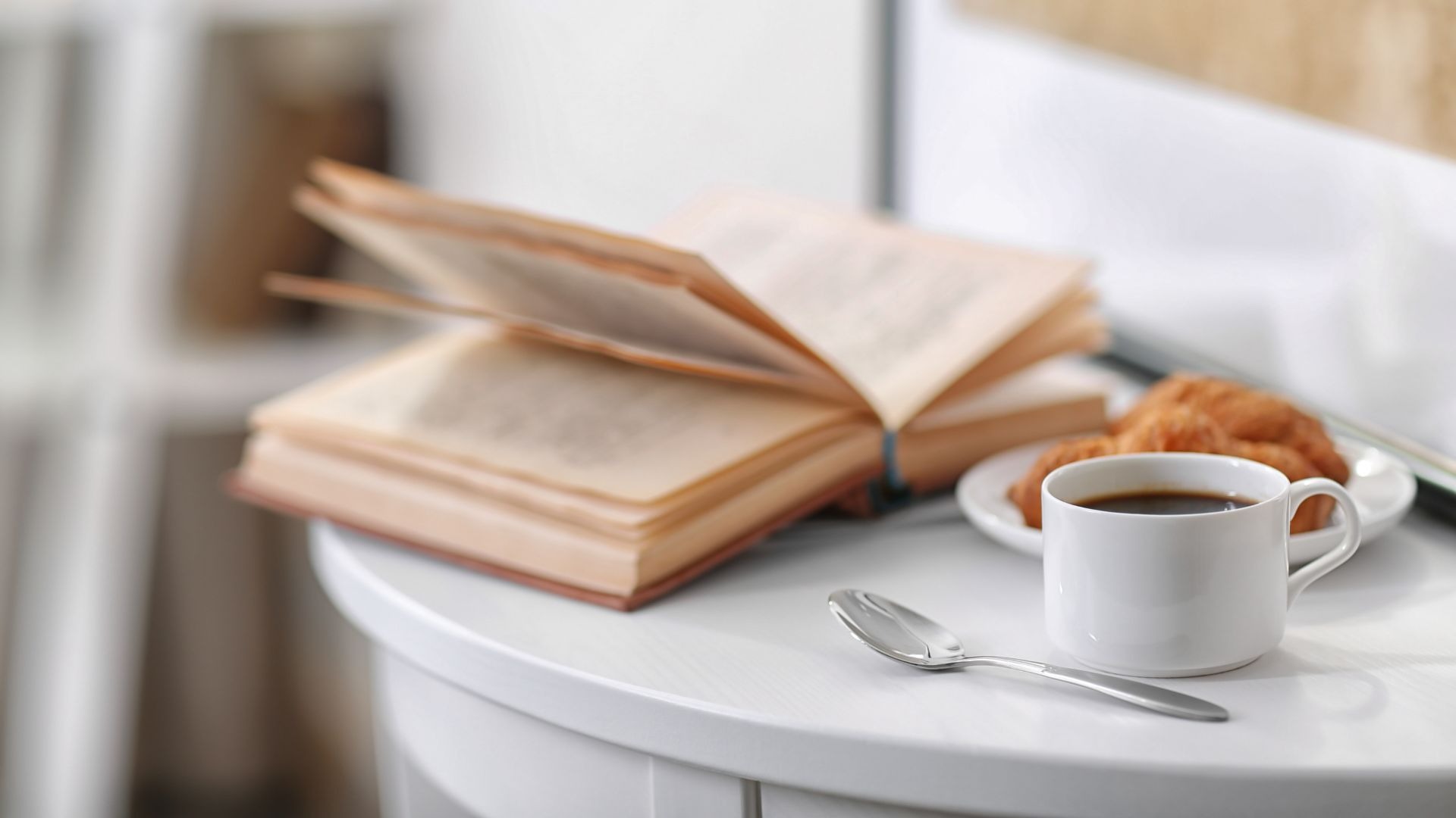 En kopp kaffe, en croissant och en öppen bok