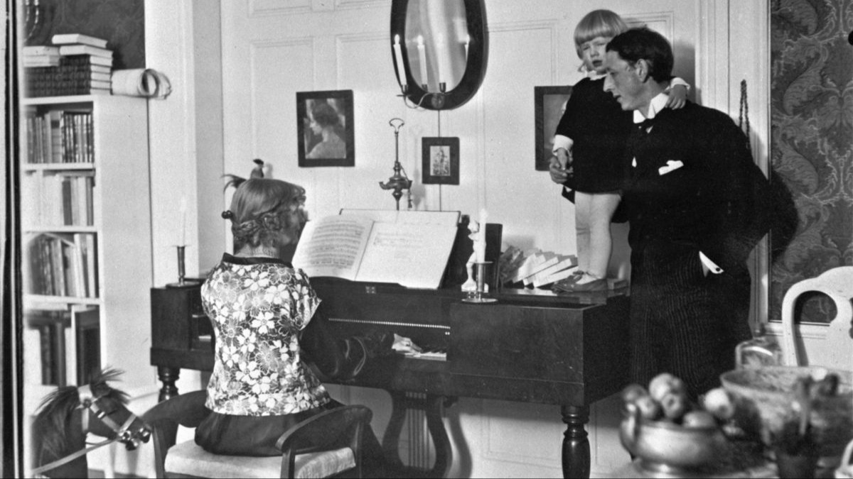 Ester Bauer spelar piano och John och Putte Bauer står bredvid
