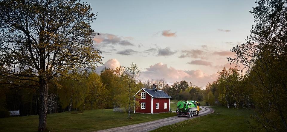 Slambil som kör längst en grusväg i solnedgången.