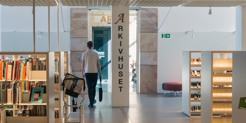 Person går in genom entrén till stadsarkivet på stadsbiblioteket.