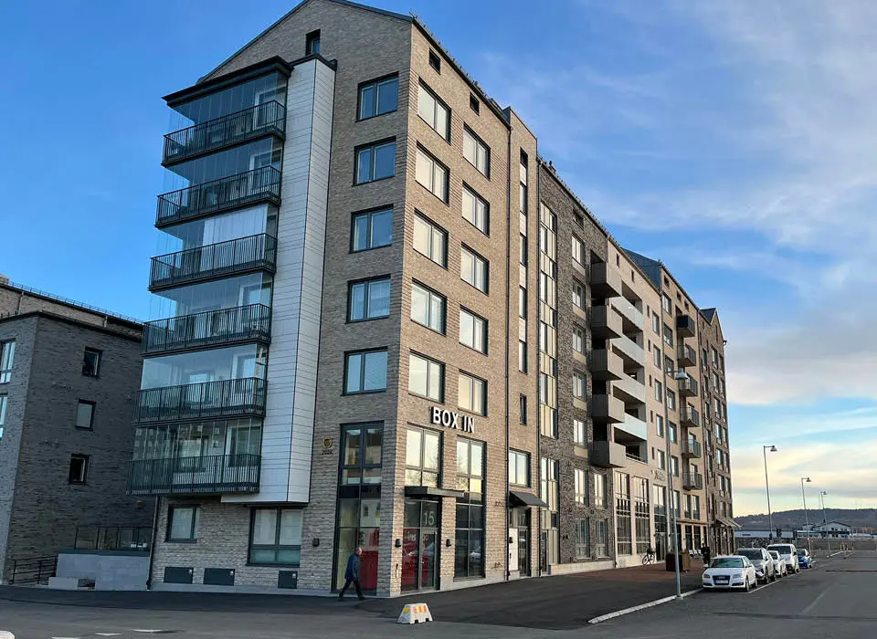 Flerbostadshus i 8 våningar med balkonger och stora fönsterpartier.