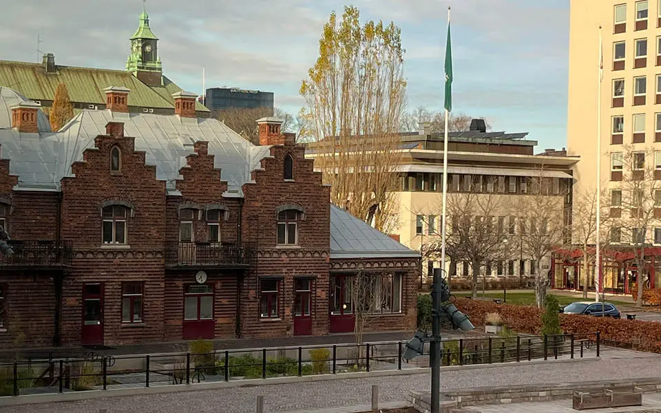 Äldre tegelbyggnad med en park framför.