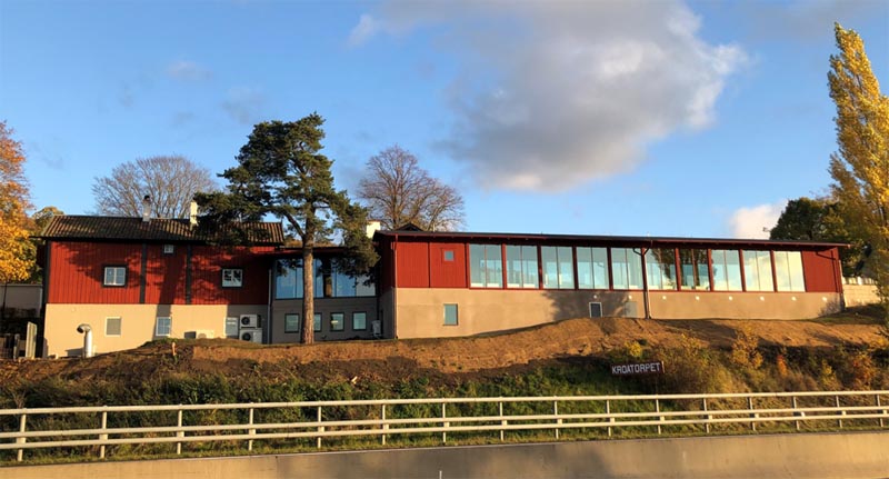 Kroatorpets utbyggnad med röd träfasad och stora glaspartier mot Vättern.