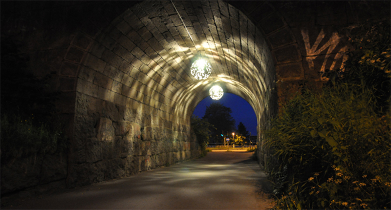 Mörk tunnel med runda lampor i taket.