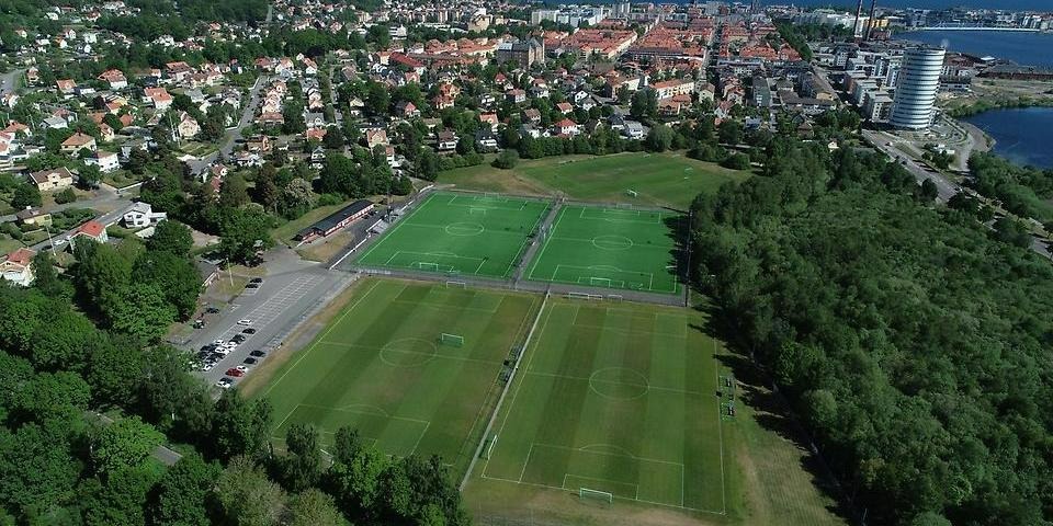 Jordbrovallen med gröna fotbollsplaner, i bakgrunden Munksjötornet och Munksjön. 