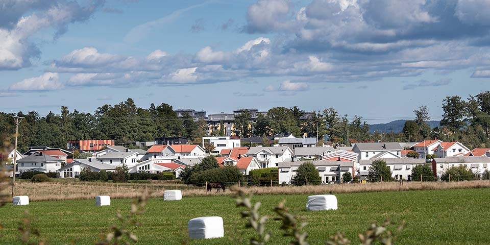 Villaområde med åkermark i förgrunden.