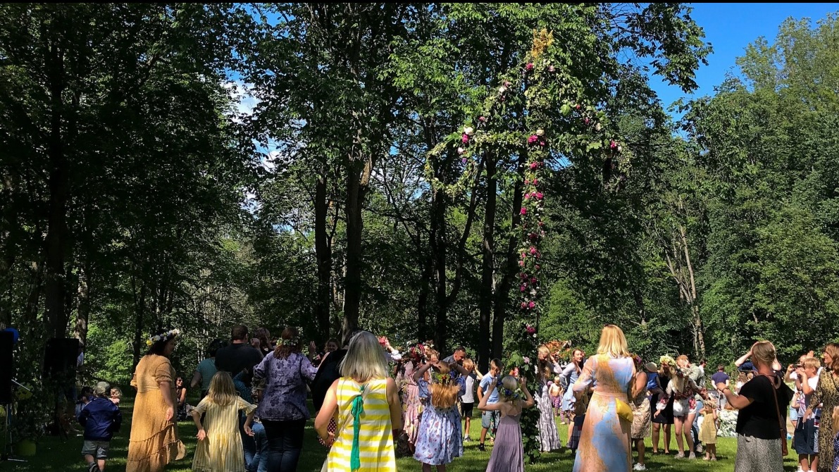 männsikor som dansar runt en midsommarstång