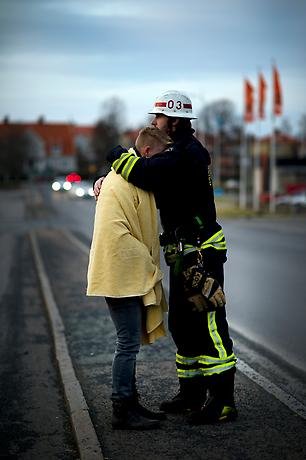 En brandman som håller om en person inlindad i en varm filt och som varit med om en kris.