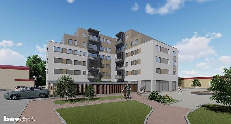 Stor grå kontorsbyggnad med gångar och gräs runt omkring.