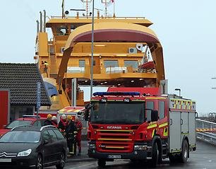 Färjan Braheborg i hamnen i Gränna. Framför den står en brandbil och några brandmän.