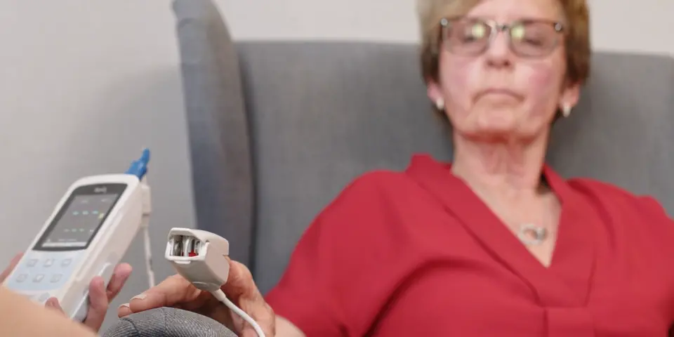 Kvinna sitter i fåtölj och får sin synenivå mätt.