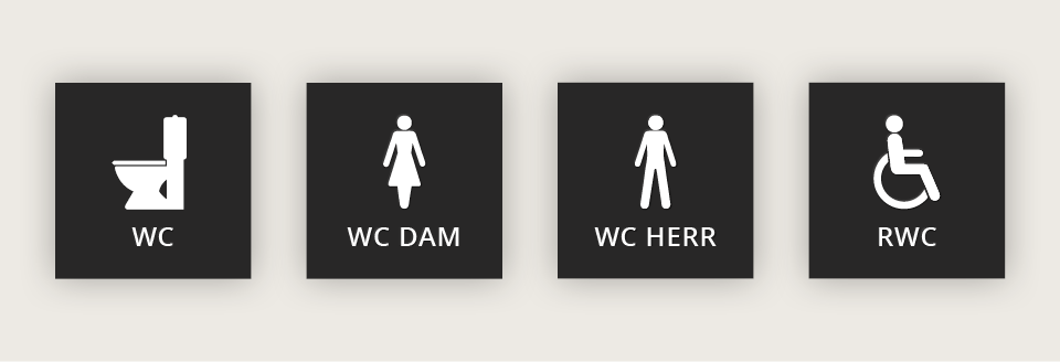 Fyra skyltar med ikoner mot svart platta som visar ikoner för wc, wc dam, wc herr och rwc.