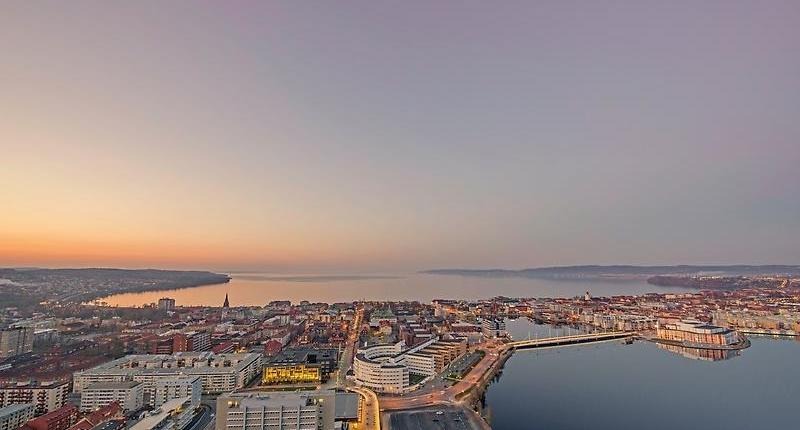vy över Jönköping vid skymning. Hustak, byggnader, Munksjön och Vättern.