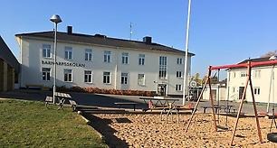 En lekpark med gungor framför Barnarpsskolans huvudbyggnad.