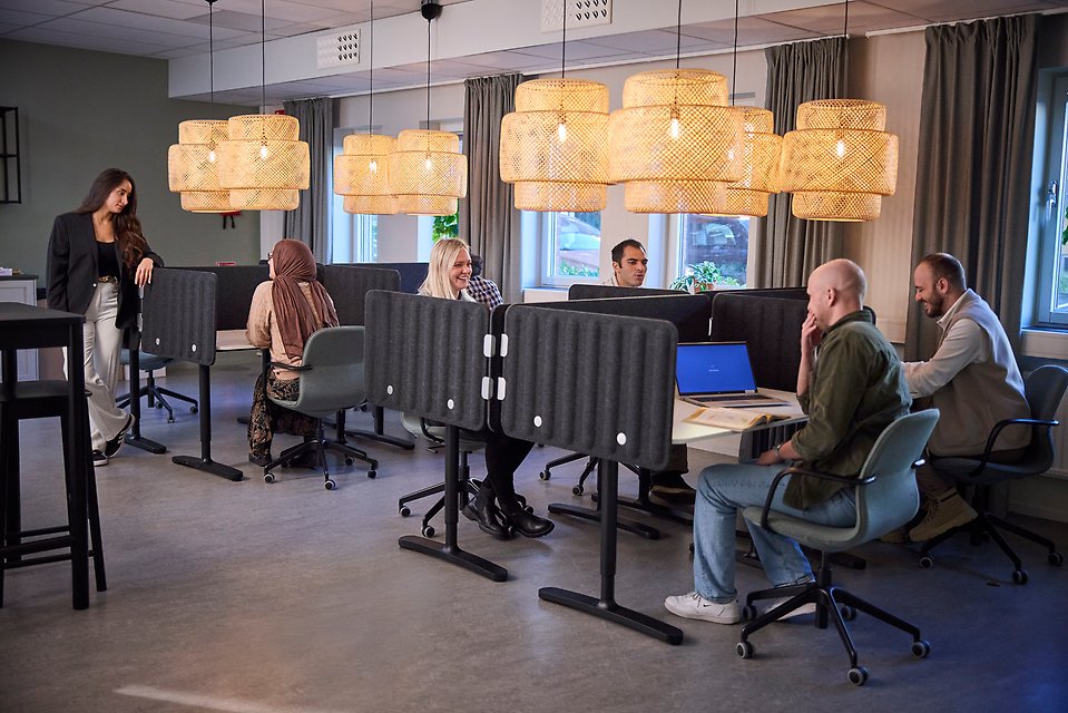 Personer som sitter vid studieplatser och arbetar framför dator