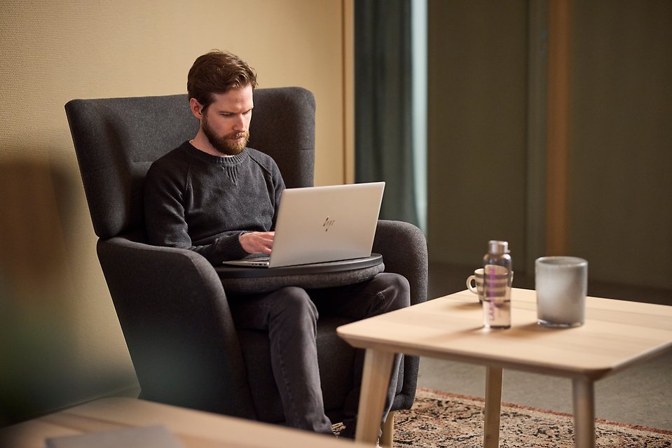 En man som sitter i fåtölj med laptop